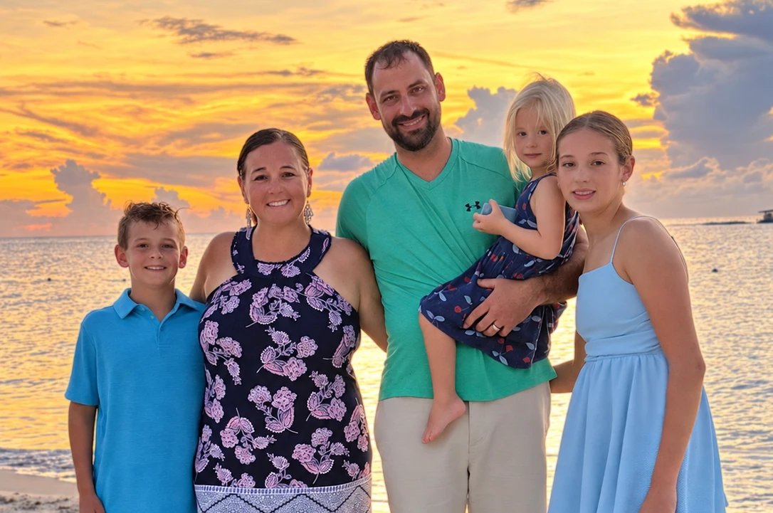Dr. Jacob Pudenz with his family on a beach at sunset